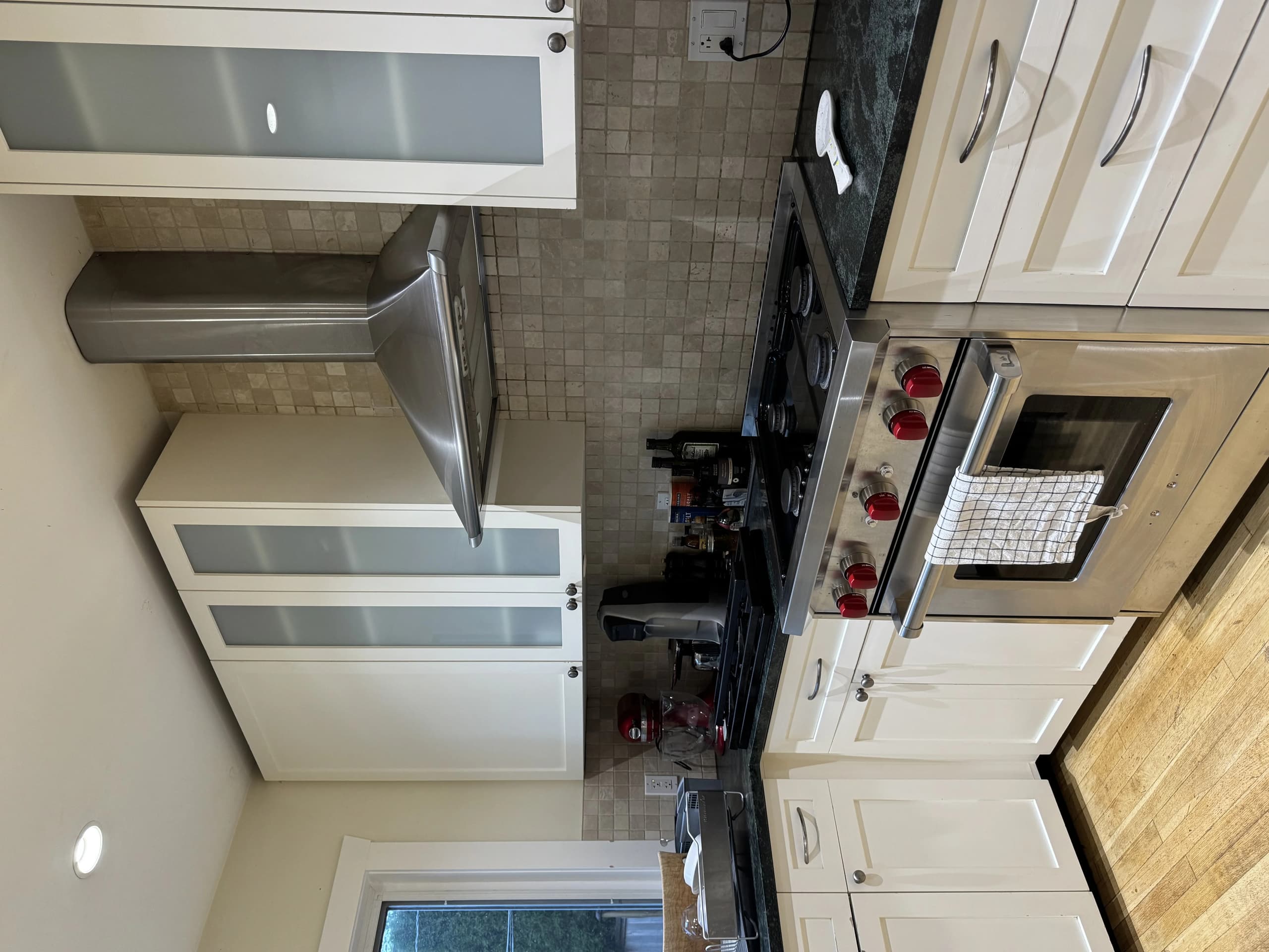 Clean, modern kitchen features white cabinets, stainless steel oven, and tiled backsplash.