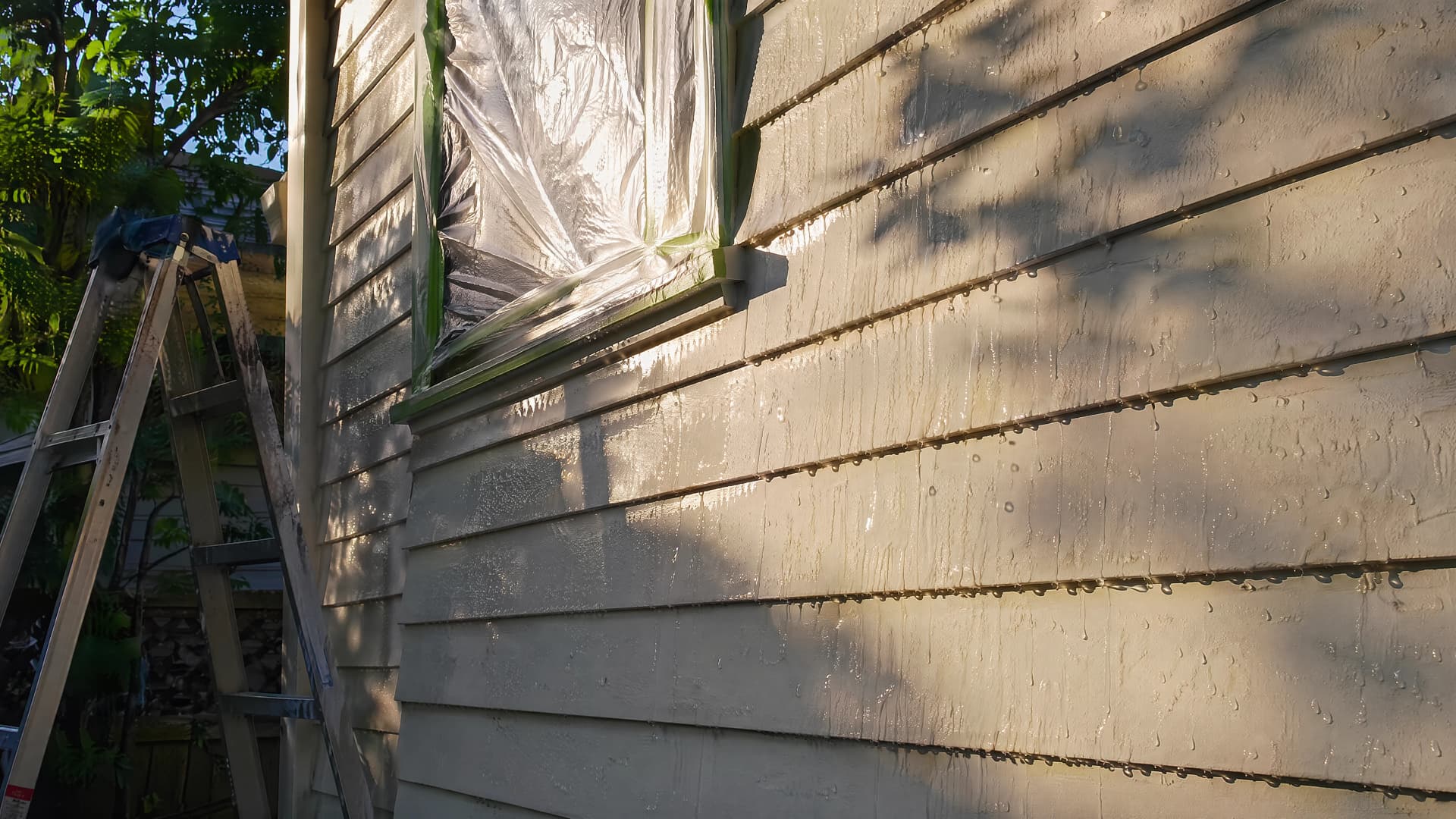 Water sheeting off freshly washed siding on a Vancouver home with a taped-off window ready for repainting