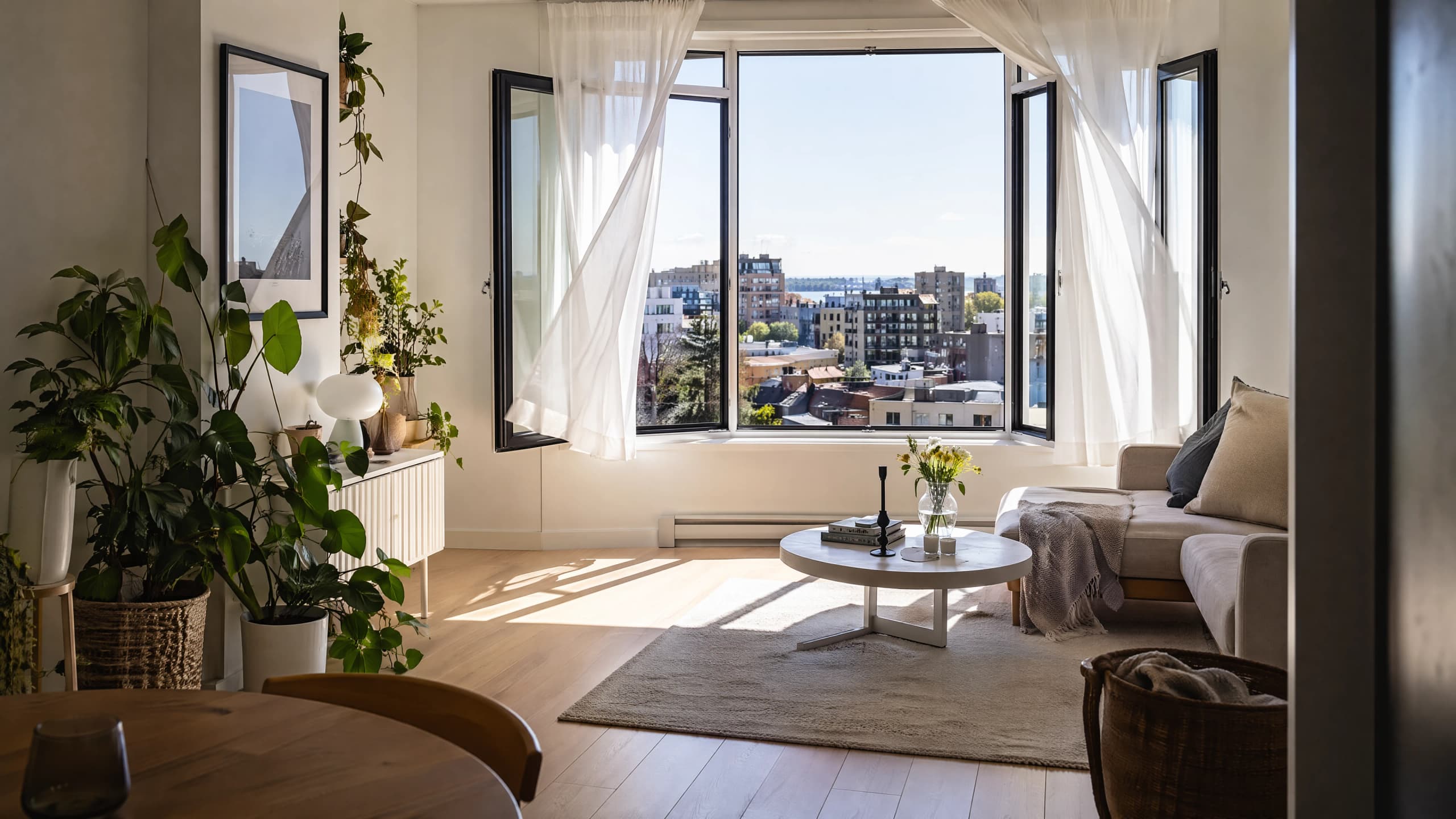 Bright Vancouver apartment living room with windows open wide to fresh air after rain, sheer curtains stirring