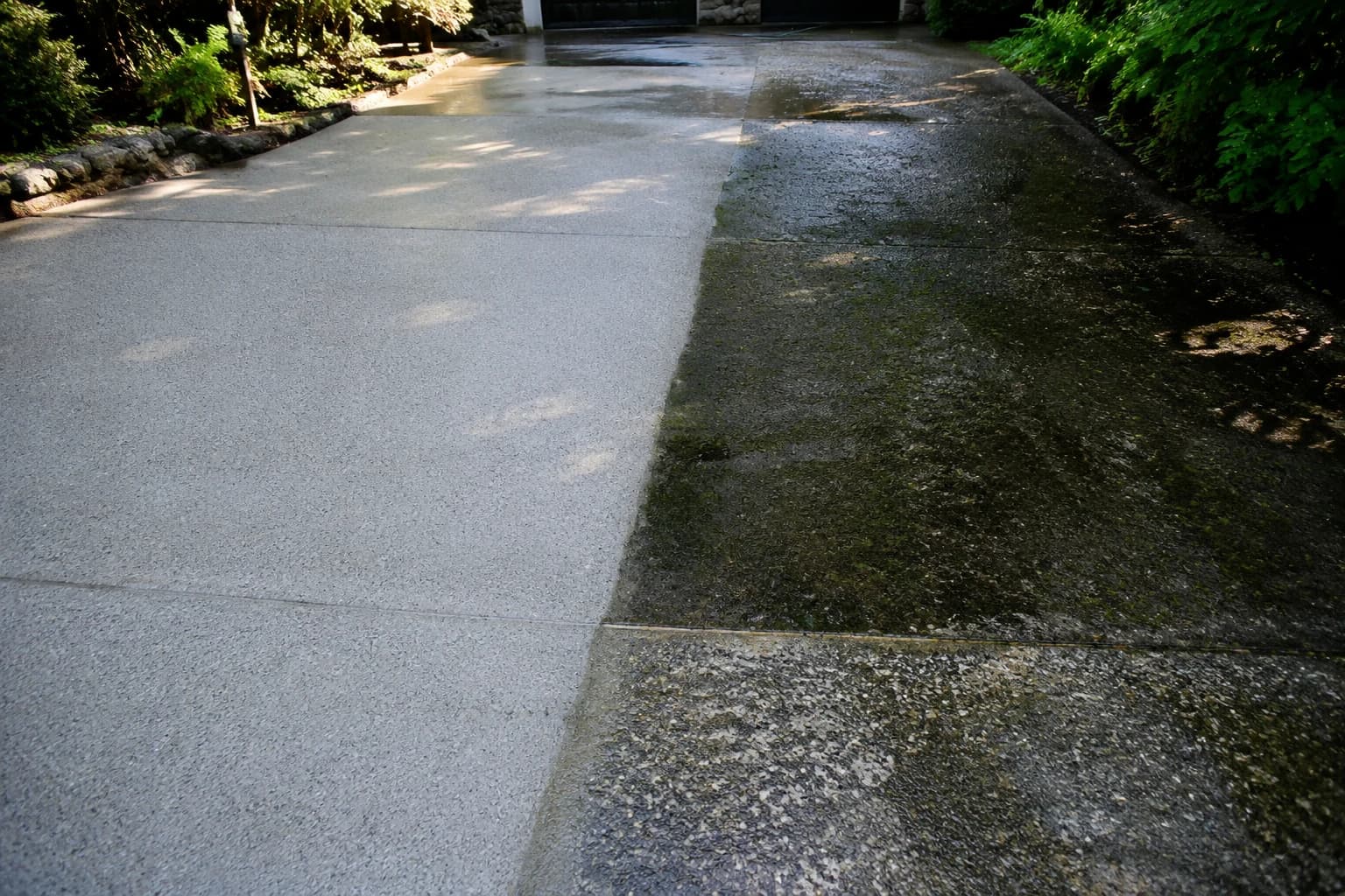 Concrete driveway half pressure-washed, one side bright and clean and the other still dark with moss and grime