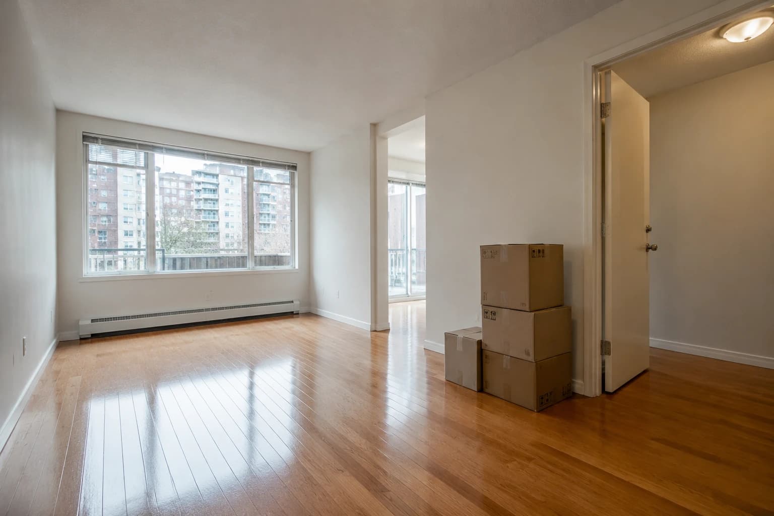 Empty Metro Vancouver apartment mid move-out with gleaming floors and moving boxes by the door