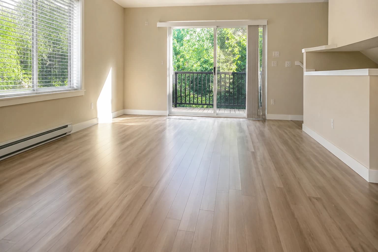 Empty Surrey townhouse living room with clean laminate floors and patio doors to greenery