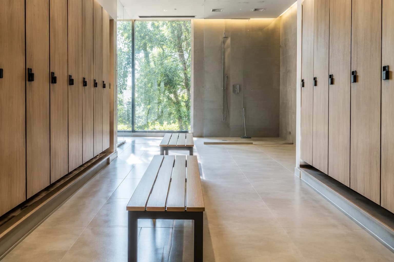 Dry, spotless gym change room with wooden benches, lockers and a squeegeed glass shower in Metro Vancouver