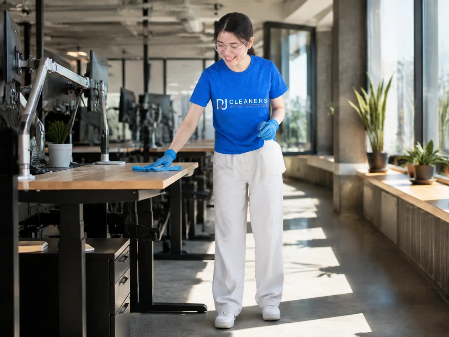 Open-plan tech office space with standing desks being wiped down by professional cleaner