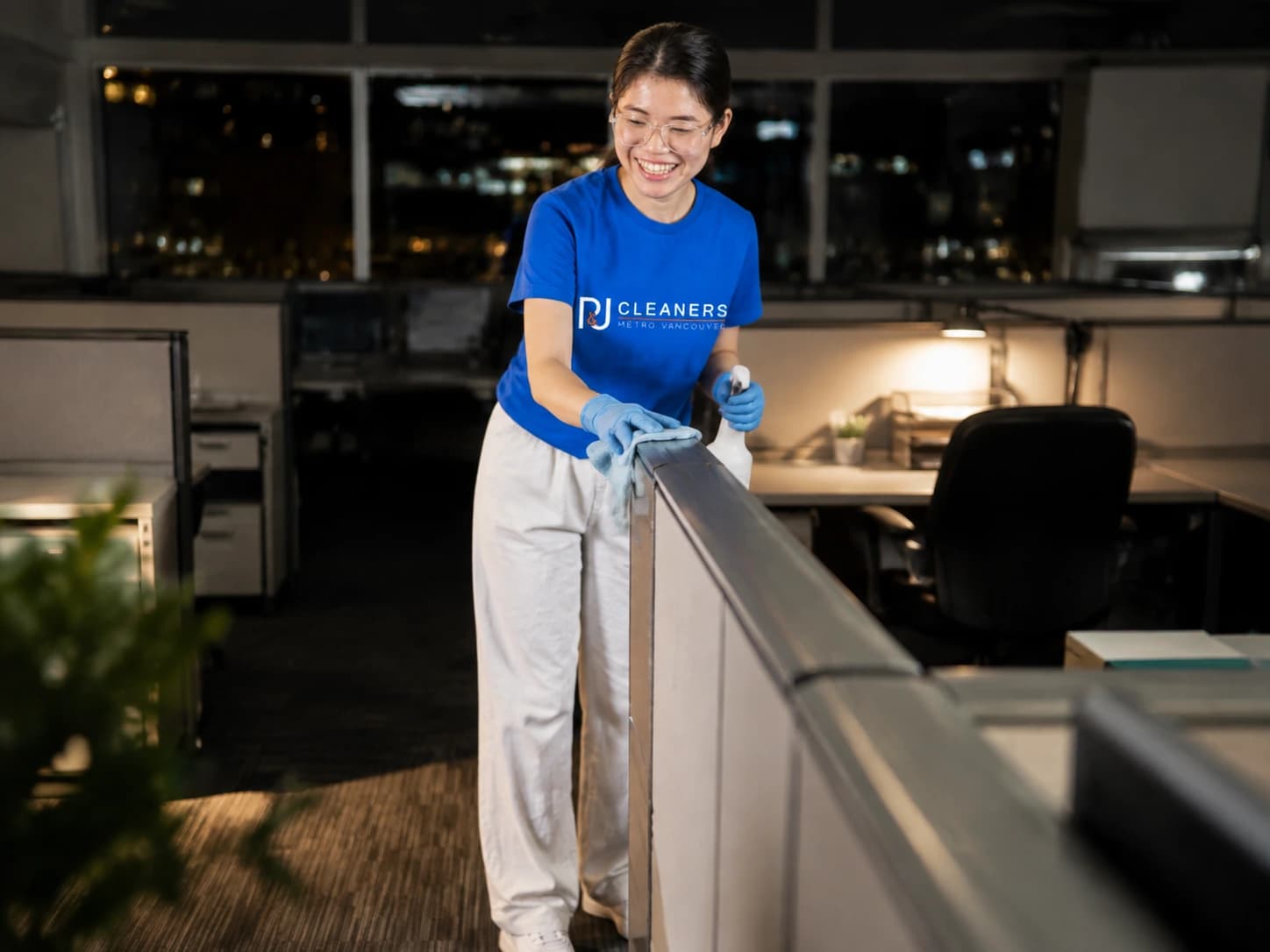 Professional cleaner sanitizing office cubicles at night
