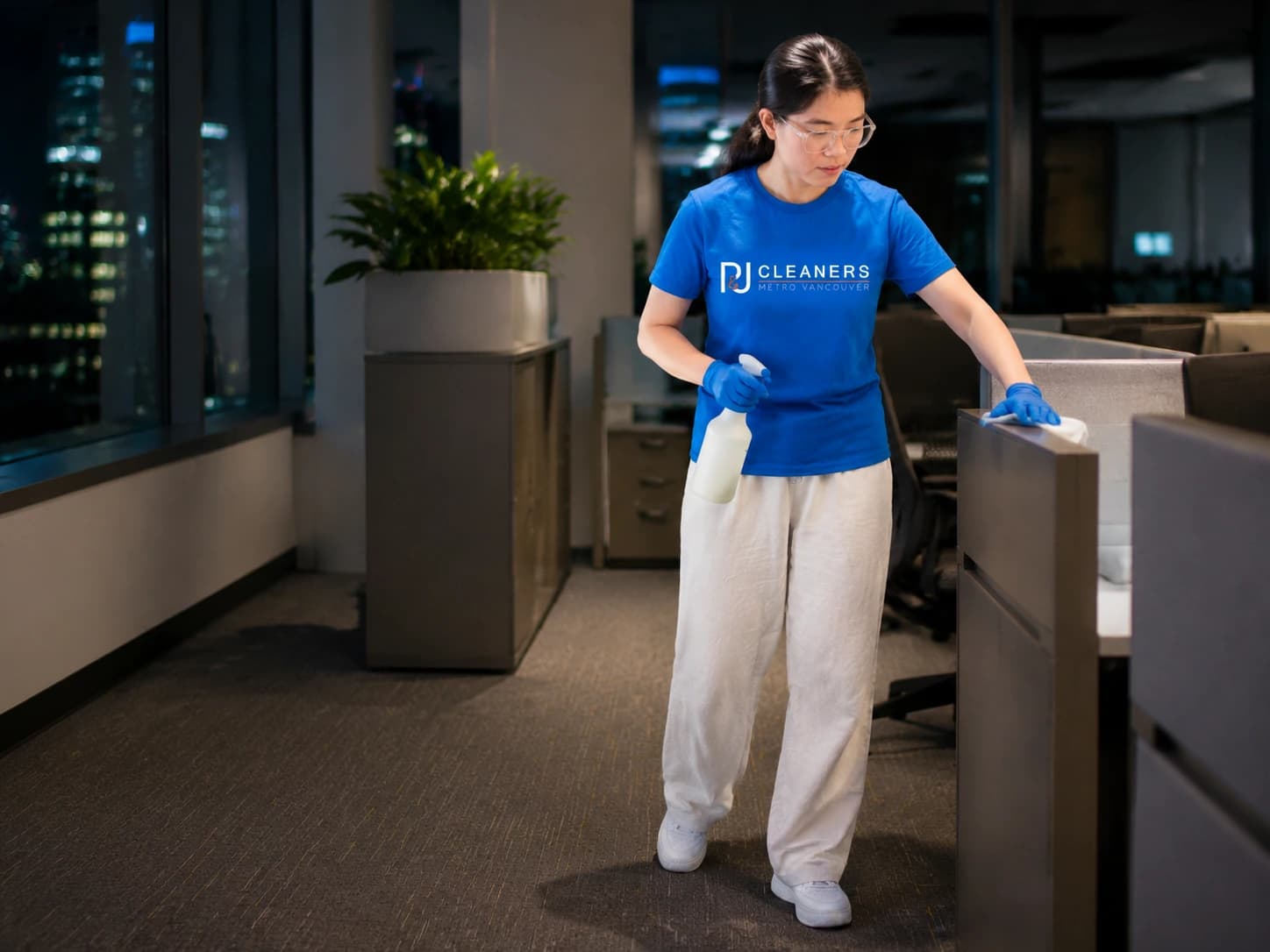Professional cleaner sanitizing office cubicles at night