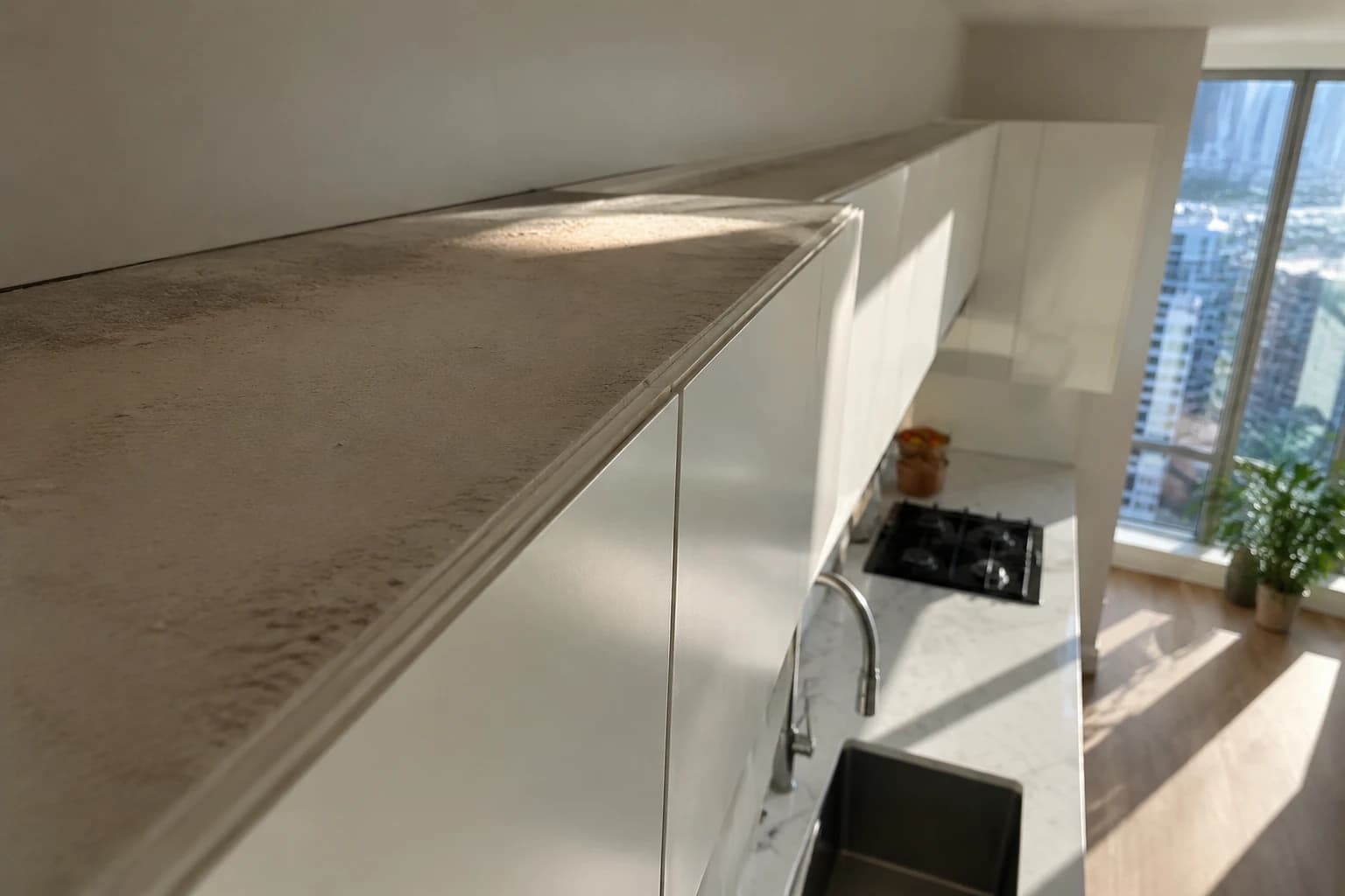Thick settled dust along the top of upper kitchen cabinets above a spotless counter in a Vancouver condo